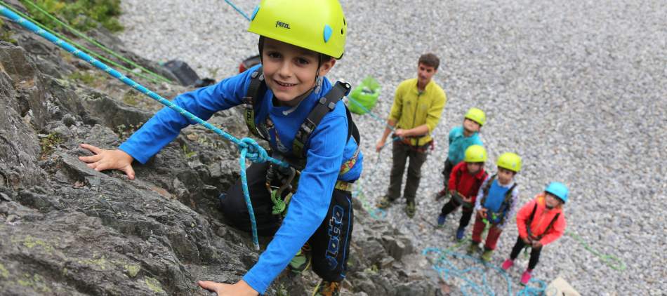 Un groupe d'enfants fait de l'escalade avec un guide au site des Gaillands à Chamonix